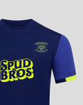 Close-up of the junior away shirt showing the crest on the chest and neon SPUD BROS logo on dark blue fabric.
