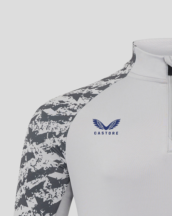 Shoulder and chest view of the midlayer showing camo sleeves and Castore logo with club crest on chest.