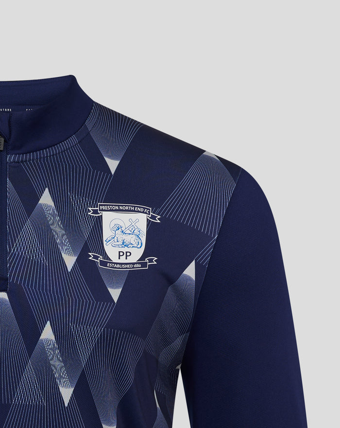 Close up of navy matchday midlayer top showing geometric pattern near shoulder and Preston North End crest