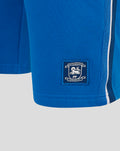Close-up of blue shorts showing an embroidered crest patch for Preston North End FC on the lower leg