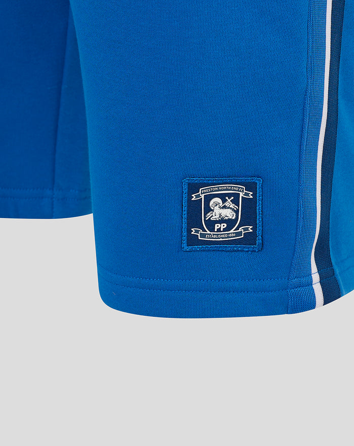 Close-up of blue shorts showing an embroidered crest patch for Preston North End FC on the lower leg