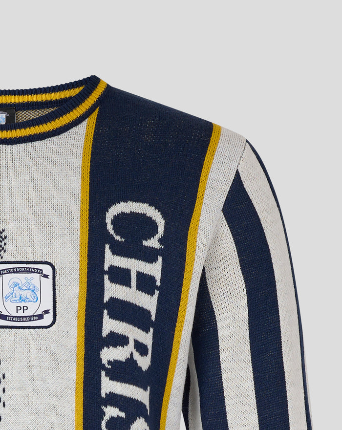 Close-up of the navy and cream Christmas jumper showing bold CHRISTMAS lettering and crest patch along a navy stripe