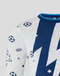 Close-up of white knit Christmas jumper showing a bold blue diagonal bolt and small star and soccer ball motifs on the shoulder.