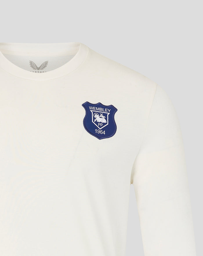 Close up of the navy Wembley crest on the chest of the cream long sleeve shirt.