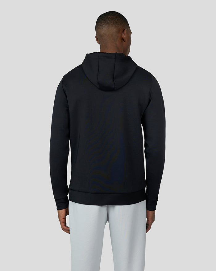 Back view of a model wearing a black Onyx Scuba Hoodie 3.0 with hood down and light gray pants.