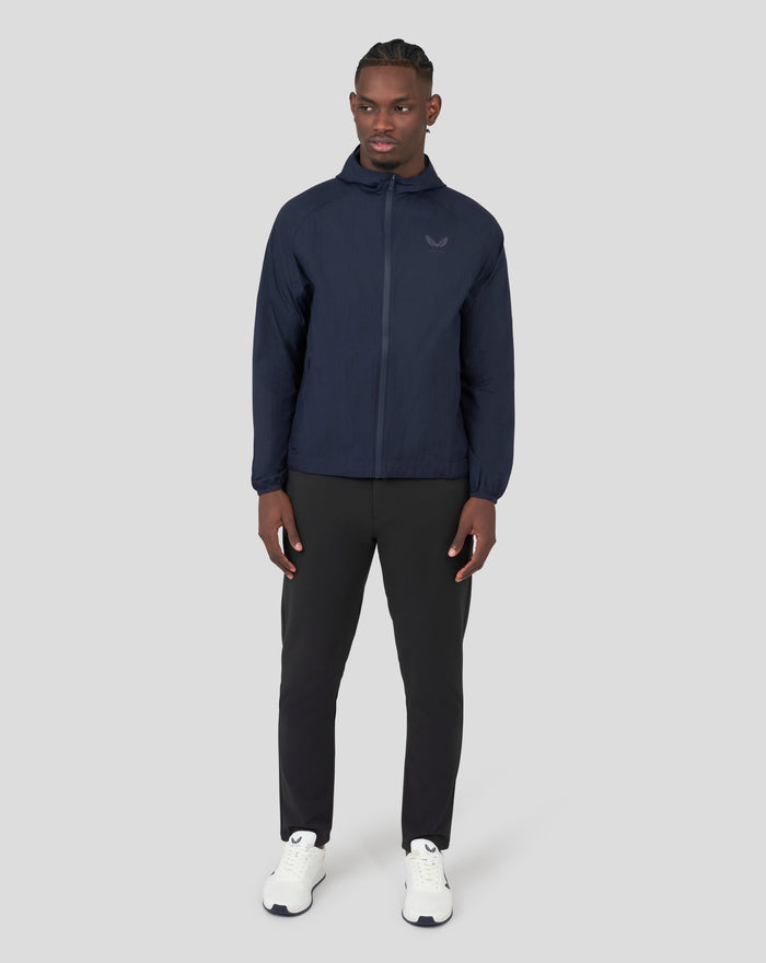 Male model wearing navy Metatek Flyweight Jacket with hood and zip front, reflective detailing