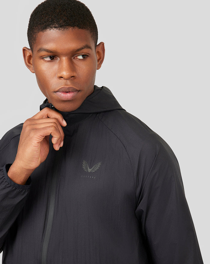 Close-up of male model wearing black hooded Onyx Metatek Flyweight Jacket with chest logo