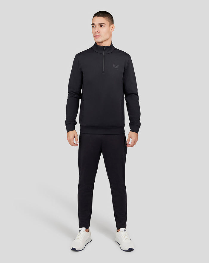 Full body front view of a man wearing the black Garcia Quarter Zip top with matching pants and white sneakers