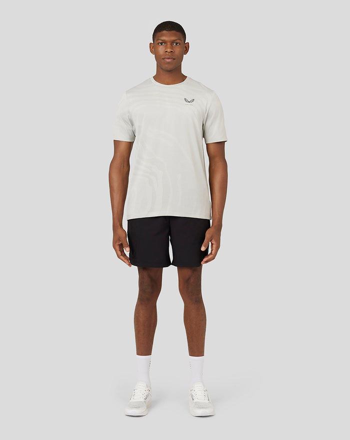 Male model wearing oyster Core Tech T shirt in light beige with bold branding on the chest.