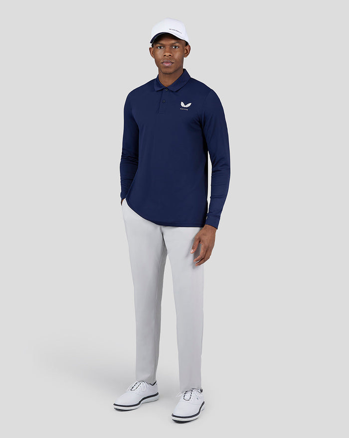 Male model wearing Midnight Golf navy Essential Long Sleeve Polo with light gray pants.
