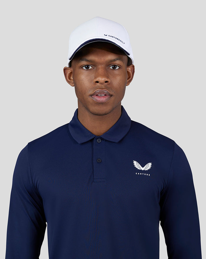 Close-up of male model in navy Essential Long Sleeve Polo with chest logo and white cap.