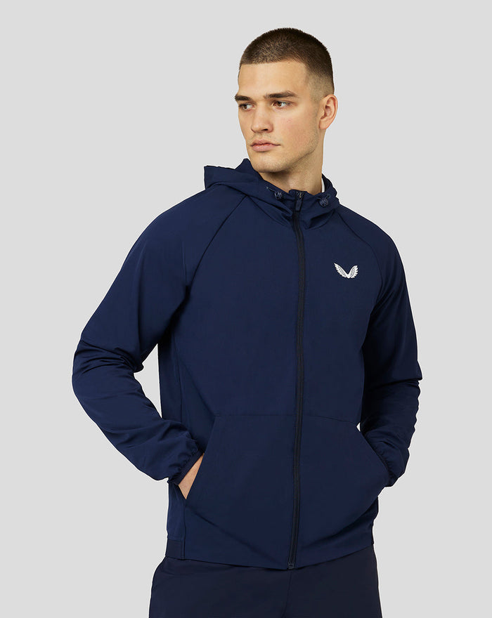 Male model wearing navy Apex Woven Hoodie with zip front drawstring hood and pockets Castore logo on left chest