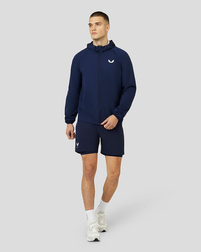 Male model wearing navy Apex Woven Hoodie with front zip, drawcord hood and side pockets.