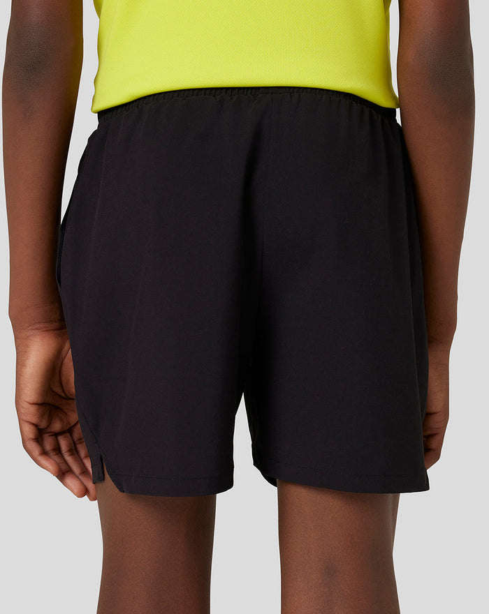Back view of black junior woven shorts with a white Castore wing logo at the hem and a side slit