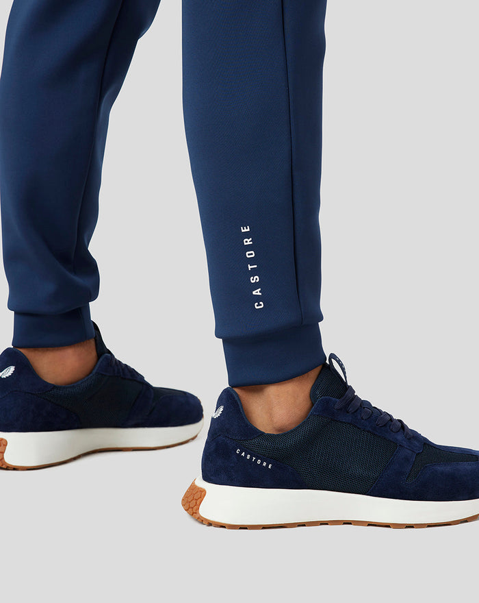 Calf height close up of navy jogger showing Castore branding along the leg and sport shoes